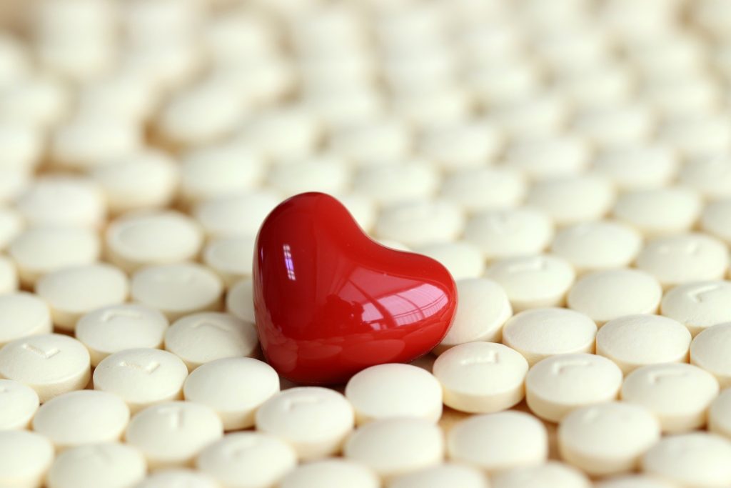 Rotes Herzsymbol liegt zwischen Tabletten