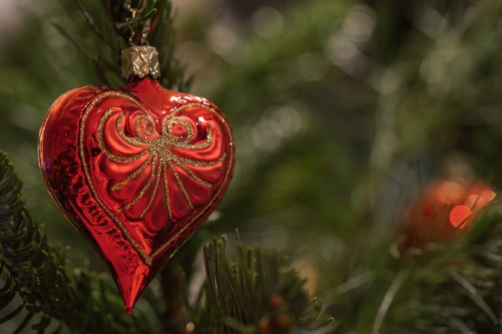 Rote Weihnachtskugel in Herzform an Tannenbaum